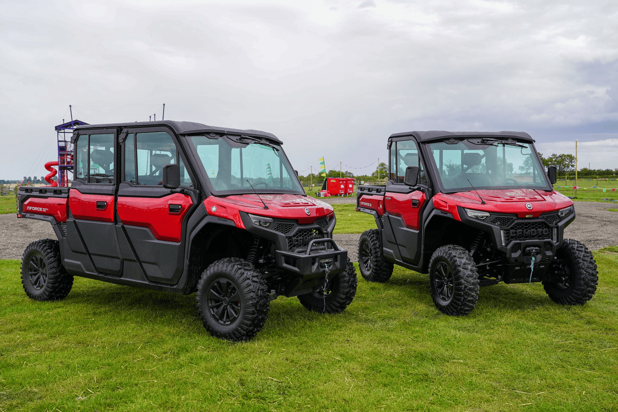 Two red CFMOTO UTV utility vehicles parked on grass in outdoor setting