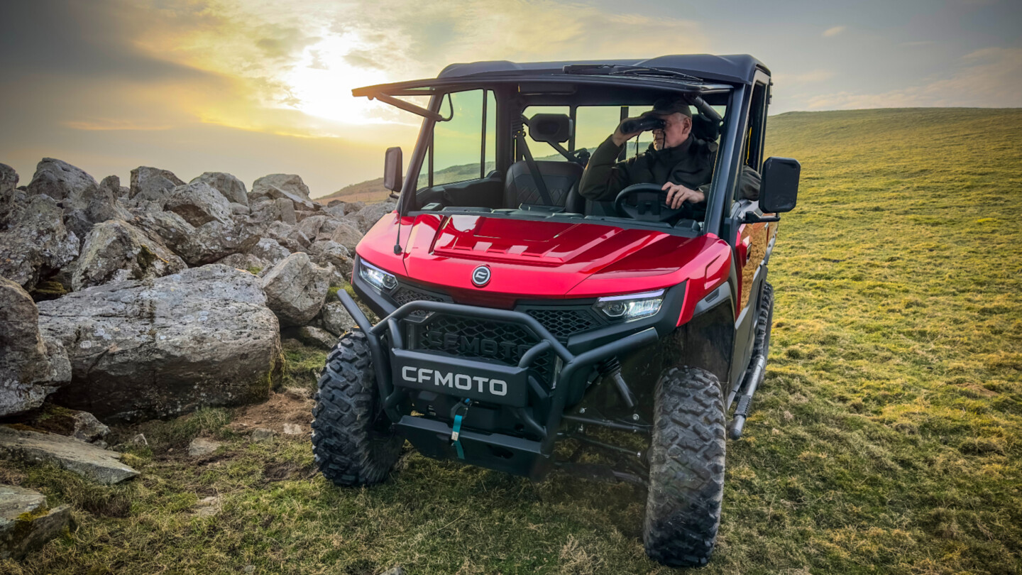 CFMOTO UTV utility vehicle driving off-road on rocky hillside with driver inside
